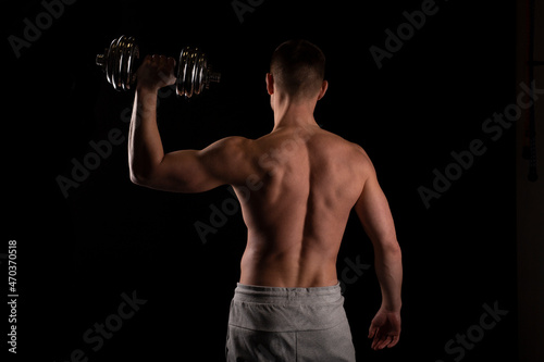Sport man Standing with Dumbbell in Hand. Man Working out with Dumbbell. Sportsman Back View