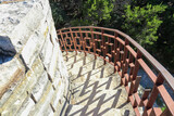 Beautiful limestone stairs leading down from a watchtower with the iron hand rail casting zigzaging shadows on the the steps at Mother Neff State Park Texas