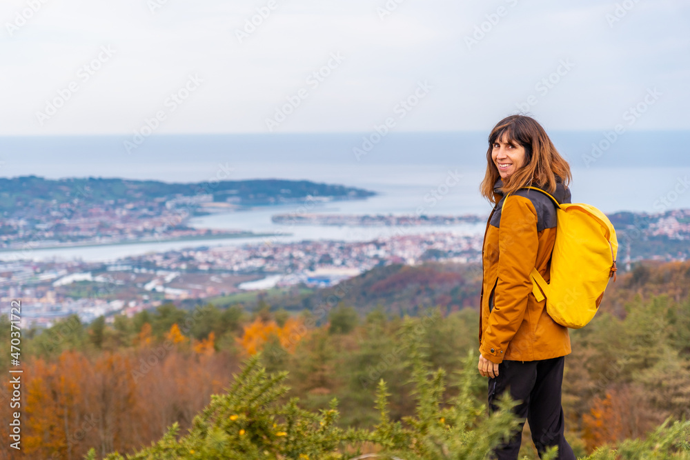 A young woman looking from the top of Erlaitz over the Bidasoa river and the municipalities of Fuenterrabia and Hendaya in the town of Irun, Gipuzkoa. Basque Country