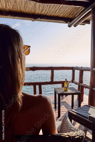 woman relaxing on terrace drinking wine on the beach looking sunset and ocean view © damianalmua