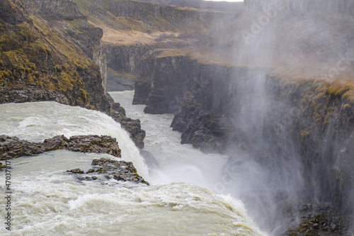 The Gullfoss waterfall in Iceland flows powerfully into a deep gorge below on an overcast mid-morning in October. 