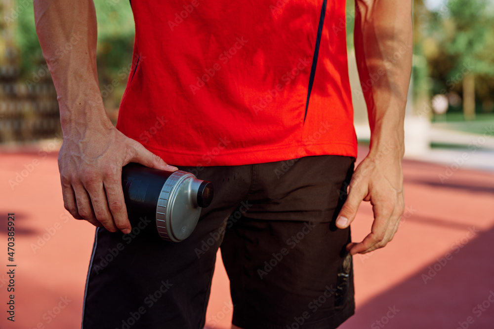 Fototapeta premium sporty man resting in the park on a bench having a snack