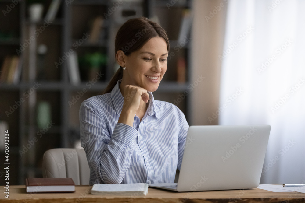 Attractive smiling business lady sit at workplace desk working on laptop. Concept of successful entrepreneur female, routine using computer, websurfing, modern tech usage and wi-fi connection concept Attractive smiling business lady sit at workplace desk working on laptop. Concept of successful entrepreneur female, routine using computer, websurfing, modern tech usage and wi-fi connection concept