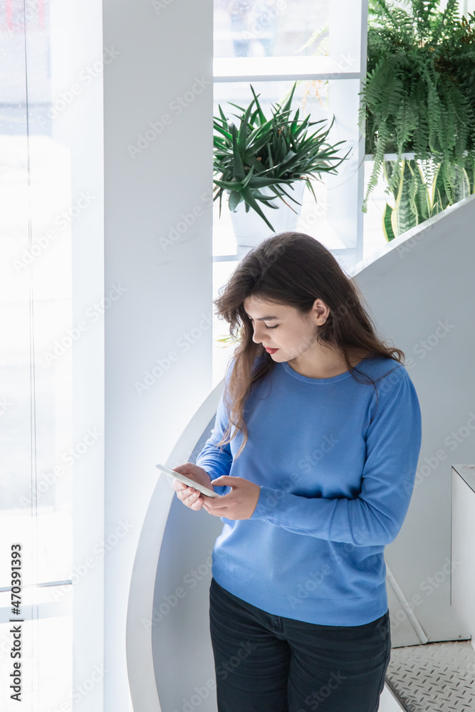 Attractive young woman in a blue sweater uses the phone. Attractive young woman in a blue sweater uses the phone.