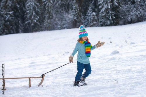 Boy sledding, enjoying sleigh ride. Child on the sleigh. Winter vacation concept.