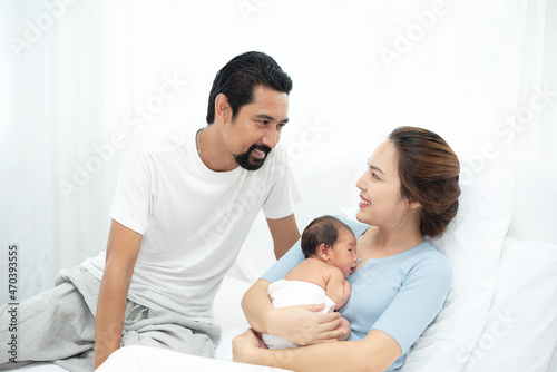 Parent and children relaxing together. Portrait of a young family with mother, father, son and daugther. Parents having happy time, welcoming newborn. © rachaphak