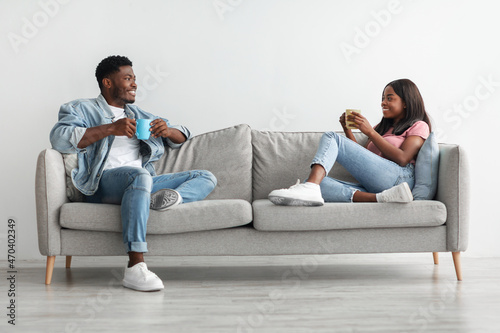 African american couple drinking coffee sitting on couch