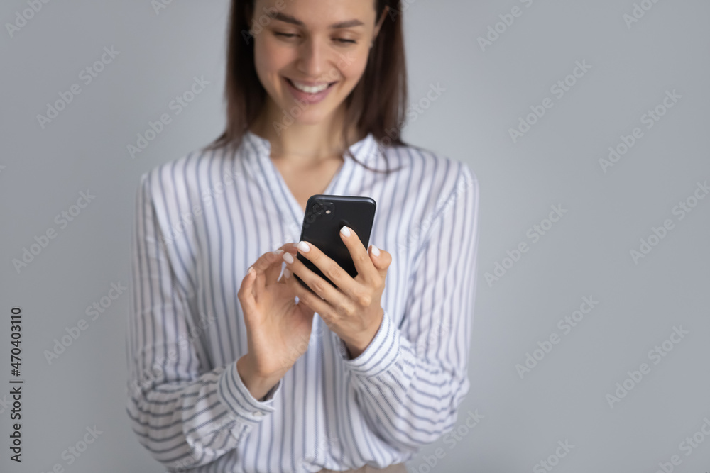 Cropped happy young woman using mobile cellphone, enjoying communicating in social network or dating application, shopping online choosing goods in internet store, posing on white studio wall.