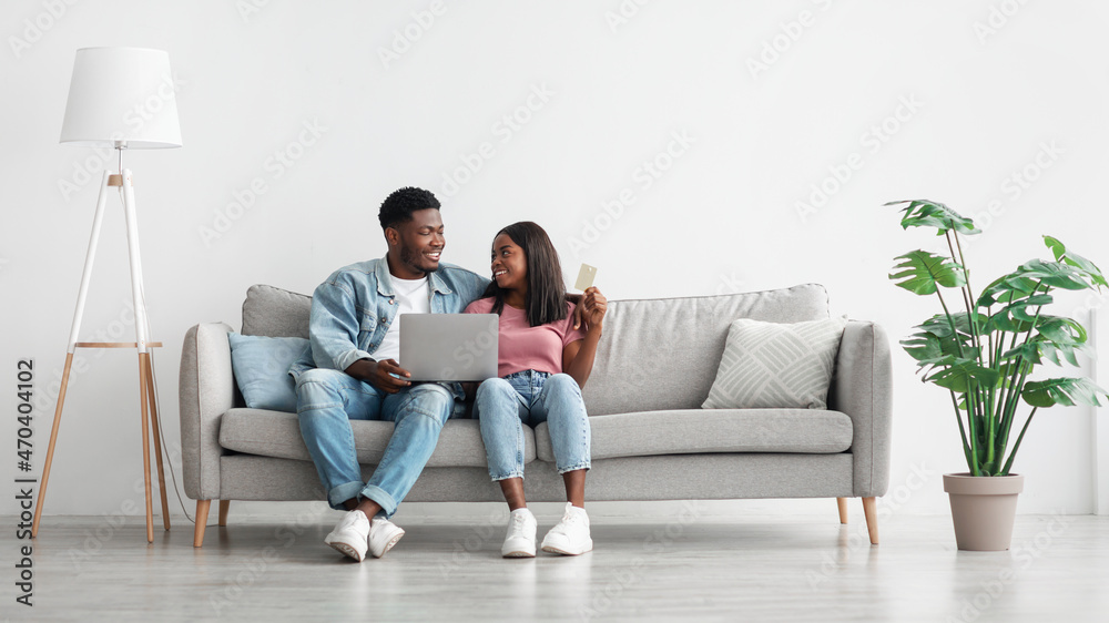 Happy black couple using pc and credit card at home