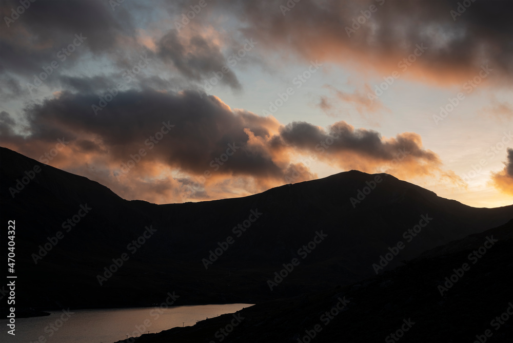 Epic moody Autumn sunset landscape image of Llyn Ogwen and Tryfan in Snowdonia National Park with stream and rocks in foreground Epic moody Autumn sunset landscape image of Llyn Ogwen and Tryfan in Snowdonia National Park with stream and rocks in foreground
