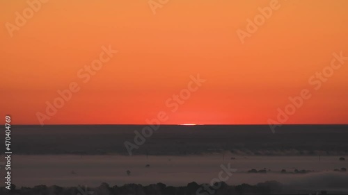 Timelapse of the movement of thick fog among fields and forests at summer dawn