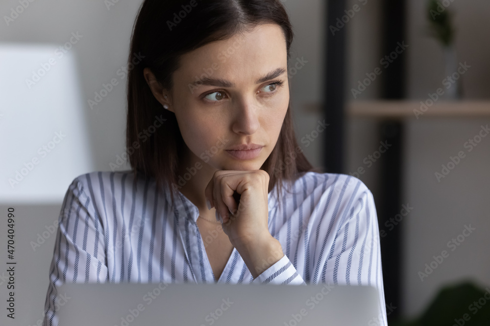 Thoughtful young business woman employee looking in distance, working on computer at home office, developing online project, pondering problem solution or considering new marketing strategy. Thoughtful young business woman employee looking in distance, working on computer at home office, developing online project, pondering problem solution or considering new marketing strategy.