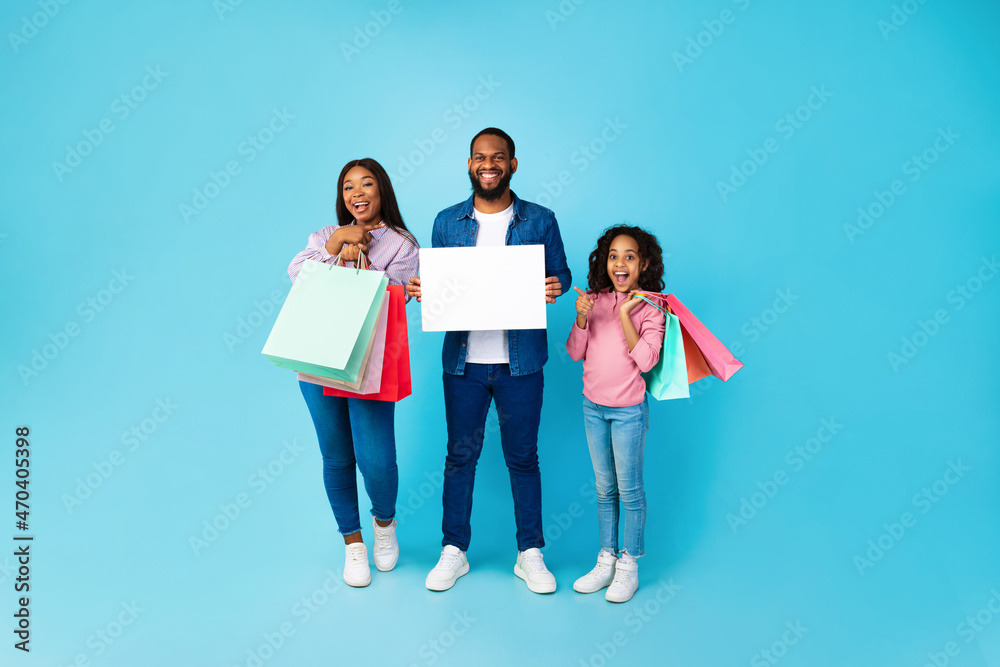 Cheerful black people holding shopping bags pointing at placard