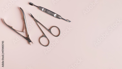 Φωτογραφία Banner manicure tools set of clipper scissors and cuticle pusher on light pink surface