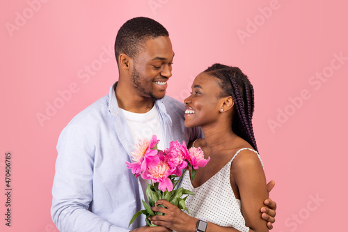 Happy black man making surprise for woman giving flowers