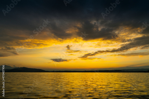 View of Lake Zugersee in the Swiss town of Zug at sunset with beautiful golden tones in the sky and reflected in the water and clouds.