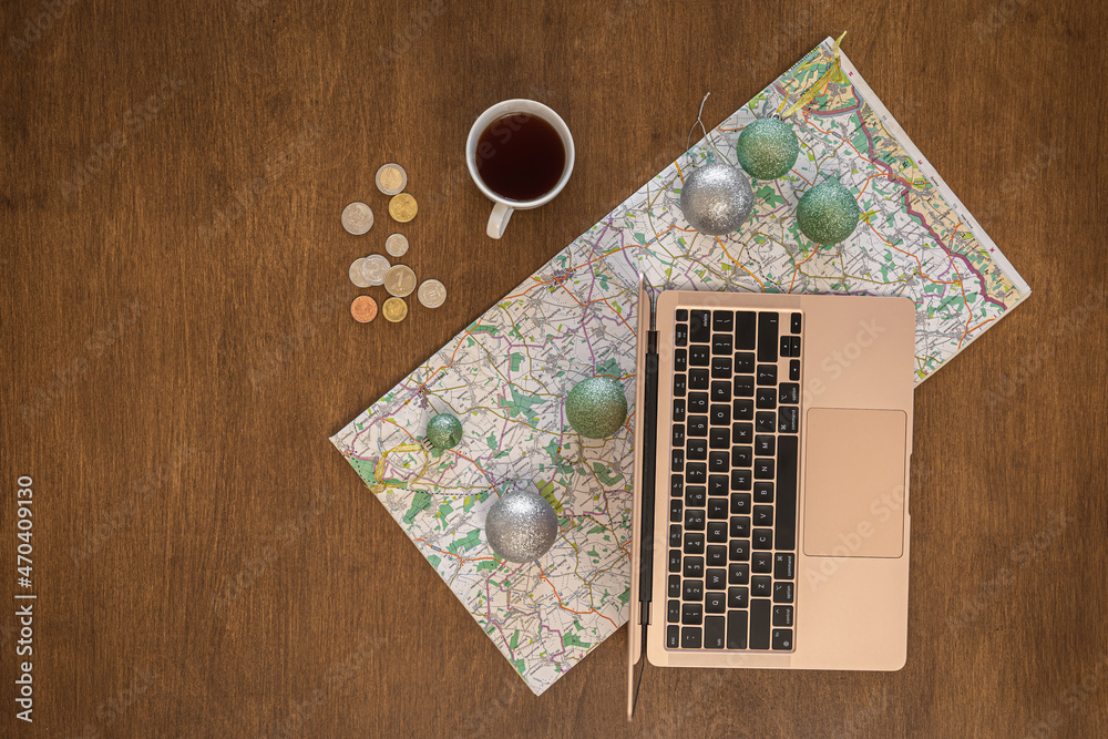 Flat lay, travel planning, laptop and map on a wooden table.
