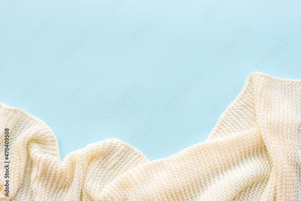 White knitted blanket on blue background. Top view, flat lay, copy space