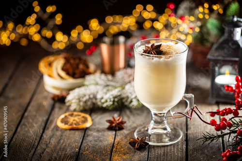Traditional winter eggnog in a glass mug with milk, rum and cinnamon, christmas decorations