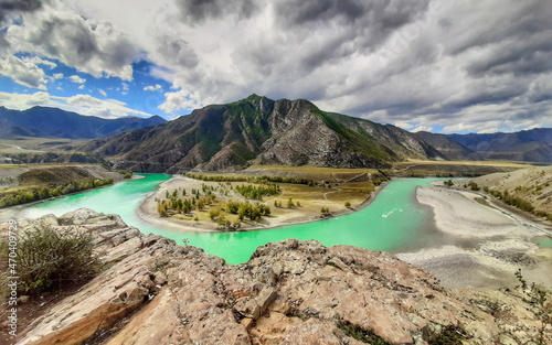 The turquoise mountain river makes a sharp turn around a part of the land and a mountain range. view from the cliff. Fuzzy blurred focus