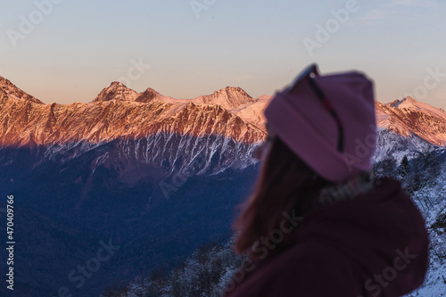 Hiker woman looking up to the sky, side view with the sun shine on the mountains in travel with the snow mountain background