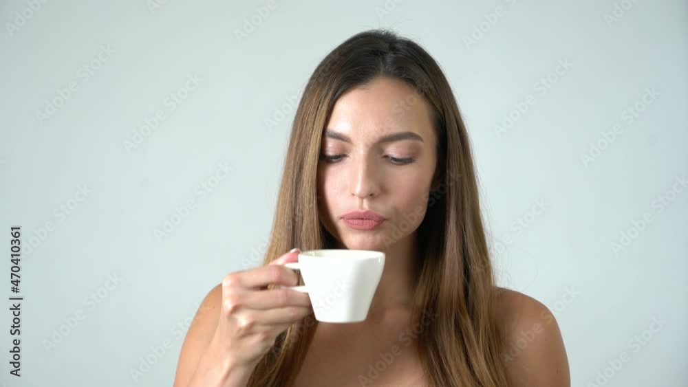 Young attractive caucasian female model drinks coffee and looks into camera white background Young attractive caucasian female model drinks coffee and looks into camera white background