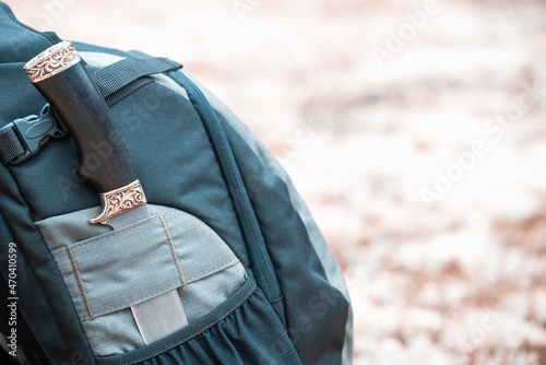Matching knife in backpack pocket in the forest. Hiking equipment.