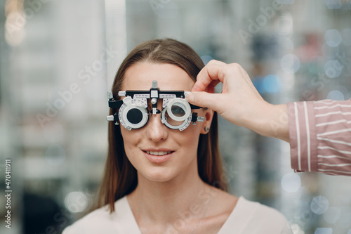 Portrait of happy young woman during eye exam at optometrist optician
