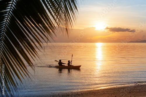 Sea sunset, ocean sunrise, tropical island beach, palm tree leaves, blue water wave, two people silhouette in boat, kayak paddle rowing, canoe sport, summer holidays, vacation leisure, travel, tourism © Vera NewSib