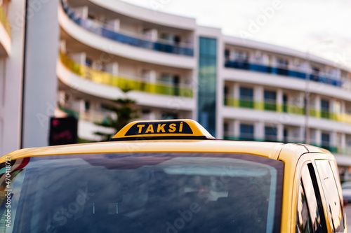 a taxi sign in turkish on the roof of a yellow car.
