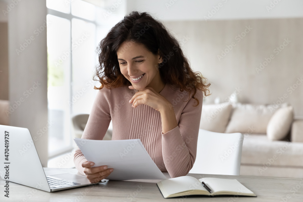 Happy businesswoman reading good news in letter, working with correspondence, sitting at desk, smiling satisfied woman freelancer received money refund, new job offer or loan approval notification Happy businesswoman reading good news in letter, working with correspondence, sitting at desk, smiling satisfied woman freelancer received money refund, new job offer or loan approval notification
