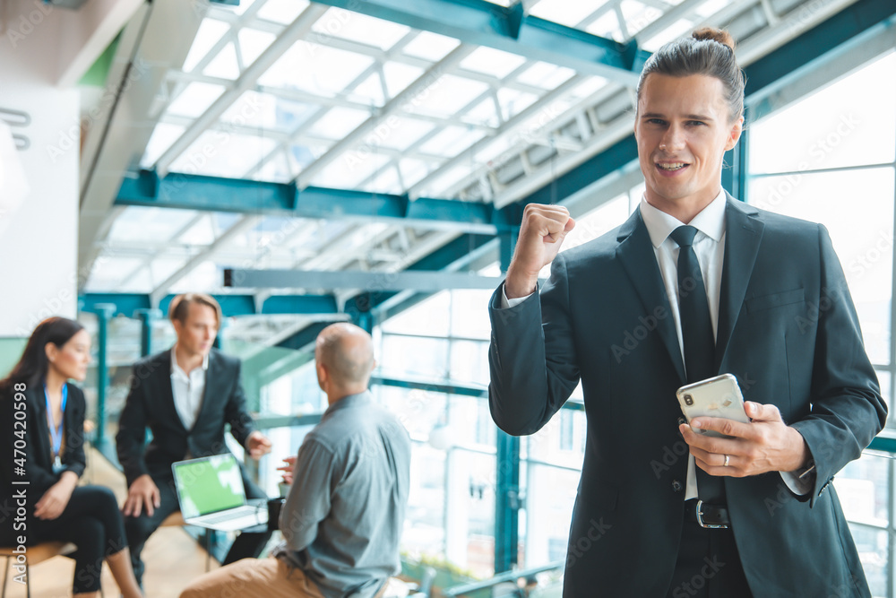 Business people applauding sitting at the table.Feeling confident in his team. Happy businessman showing his smiling while his colleagues standing in the background. Business people applauding sitting at the table.Feeling confident in his team. Happy businessman showing his smiling while his colleagues standing in the background.