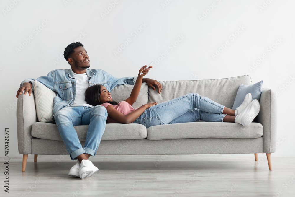 Young black woman switching on air conditioning at home Young black woman switching on air conditioning at home