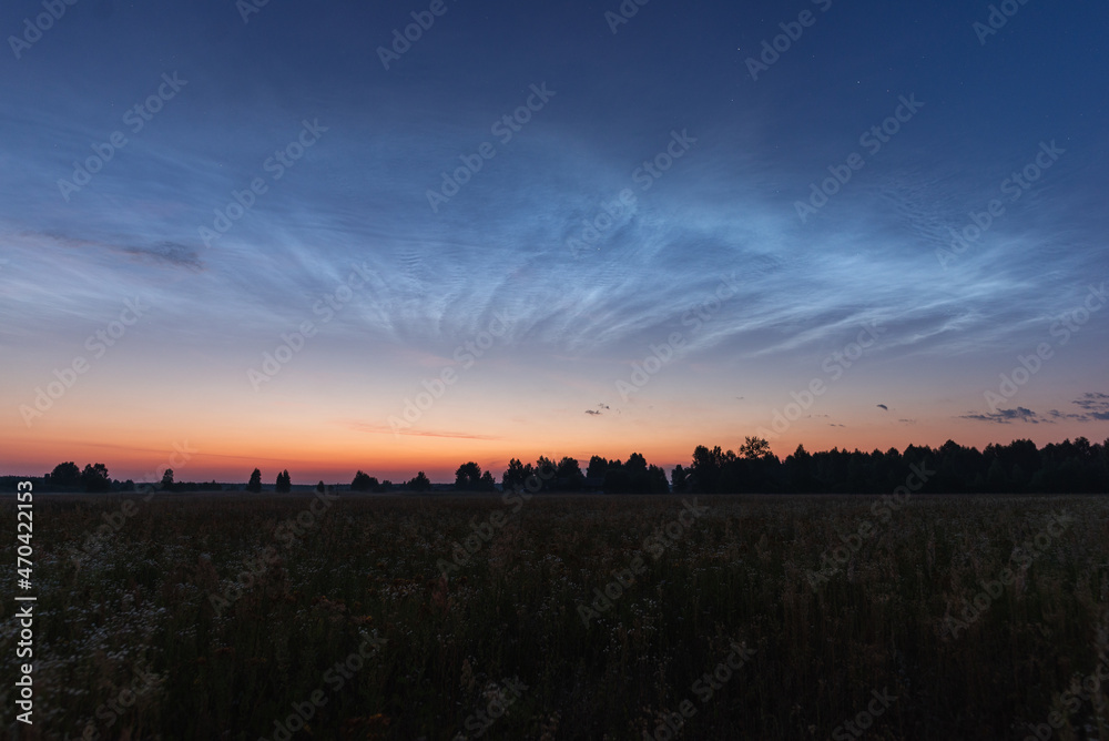 Noctilucent clouds on a summer night above p. Glowing clouds in the night sky.