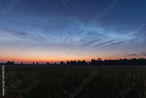 Noctilucent clouds on a summer night above p. Glowing clouds in the night sky.