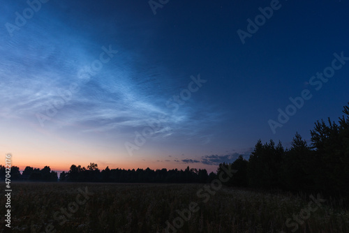 Noctilucent clouds on a summer night above p. Glowing clouds in the night sky.