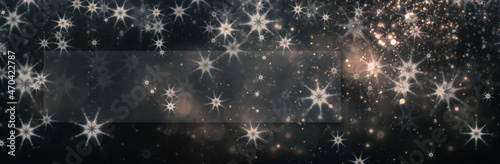 Snowflakes and bokeh blured lights on the dark background with rectangular frame for your holiday inscriprion. New Year and Christmas greeting card background with copy space.