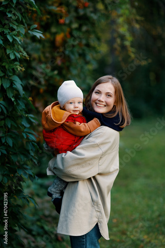 mother with a baby in her arms on a walk. A woman with a child in nature in the park