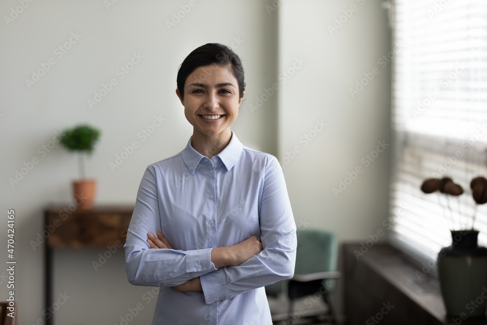 Head shot portrait smiling Indian woman with folded hands standing in modern office room, successful confident businesswoman entrepreneur looking at camera, posing for corporate profile picture - obrazy, fototapety, plakaty 