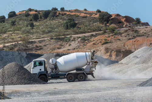 Foto Concrete mixer truck driving between mountains of sand and gravel in a quarry