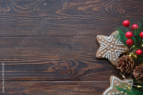 Christmas background with gingerbread cookies with a spruce branches and pine cones and wooden brown texture