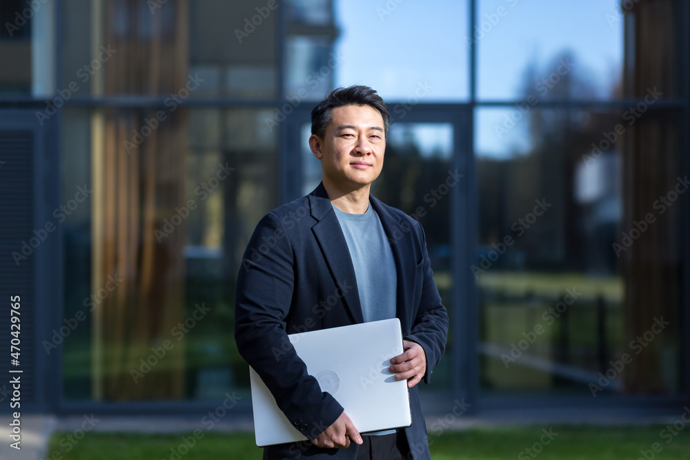 portrait handsome Asian man a university college teacher, businessman, scientist or educator. Standing background modern office center or campus with arms crossed Outside, outdoors looking at camera portrait handsome Asian man a university college teacher, businessman, scientist or educator. Standing background modern office center or campus with arms crossed Outside, outdoors looking at camera