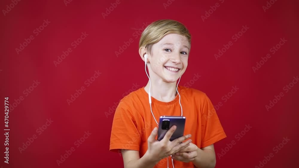 boy on a red background laughs and holds a phone in his hand, then begins boy on a red background laughs and holds a phone in his hand, then begins
