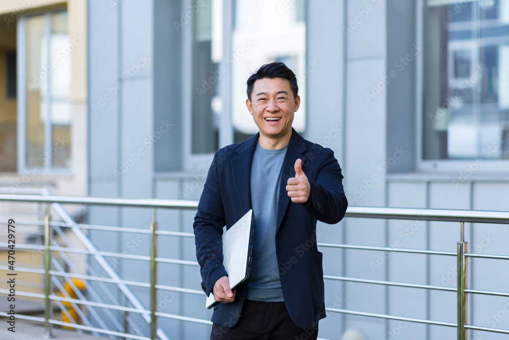 portrait handsome Asian man a university college teacher, businessman, scientist or educator. Standing background modern office center or campus with arms crossed Outside, outdoors looking at camera portrait handsome Asian man a university college teacher, businessman, scientist or educator. Standing background modern office center or campus with arms crossed Outside, outdoors looking at camera