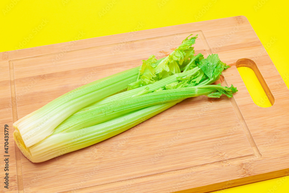 Fresh Celery Stem on Wooden Cutting Board. Vegan and Vegetarian Culture. Raw Food. Healthy Diet with Negative Calorie Content Fresh Celery Stem on Wooden Cutting Board. Vegan and Vegetarian Culture. Raw Food. Healthy Diet with Negative Calorie Content