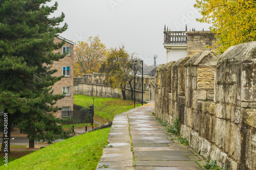 Part of trail at top of medieval 13th century stone city wall through colorful autumn foliage in York England photo