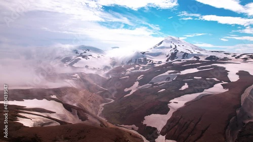 Magical aerial shot in Iceland approaching snow covered mountains with fog and steam from hot springs below. Epic view shot in highlands.