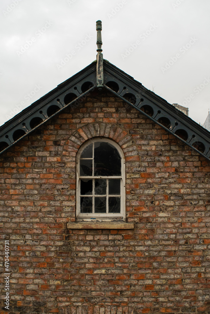 Old broken window at roof of a traditional British brick house