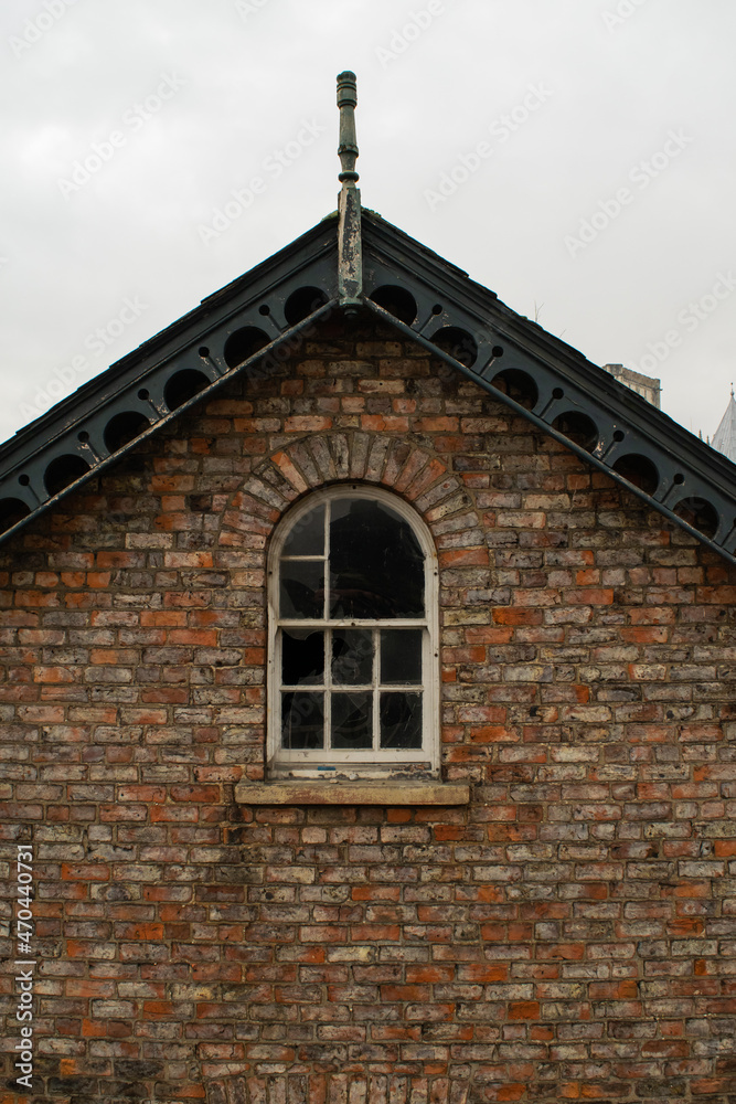 Old broken window at roof of a traditional British brick house Old broken window at roof of a traditional British brick house