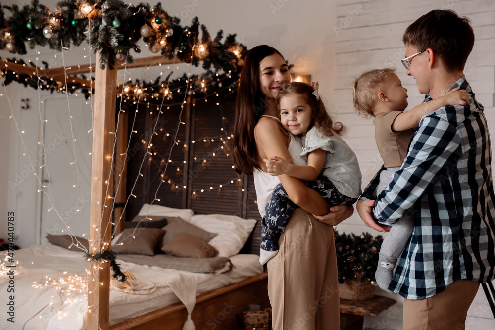 Fototapeta premium Beautiful young family near a Christmas tree on Christmas Eve